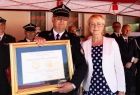 Iwona Gibas z zarządu województwa przekazuje Nagrodę Samorządu Województwa Złoty Medal Polonia Minor przyznaną z okazji 100-lecia OSP Broszkowice 