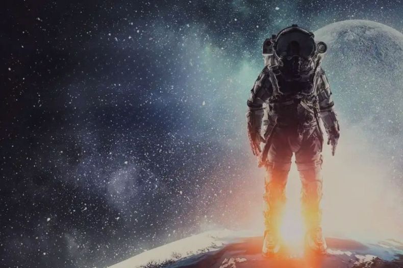 kosmonauta stojący na kuli ziemskiej a w tle promienie słoneczne